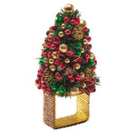 Kim Seybert Tinsel Tree napkin ring topped with a miniature Christmas tree decorated with red and green ornaments, gold bells, and pinecones for holiday dining.