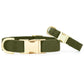 Two neutral olive green fabric collars from The Foggy Dog, featuring gold hardware buckles and D-rings, are displayed on a white background.