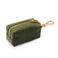 The Waste Bag Dispenser in Olive by The Foggy Dog is a small green fabric pouch featuring a gold zipper and a matching gold clip at one end, displayed against a white background. This chic dog accessory discreetly holds your waste bags and keeps them stylishly at hand during every walk.
