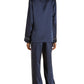 Someone is seen from the back wearing the Olivia von Halle Coco Silk Pajamas, a matching navy set with white piping.