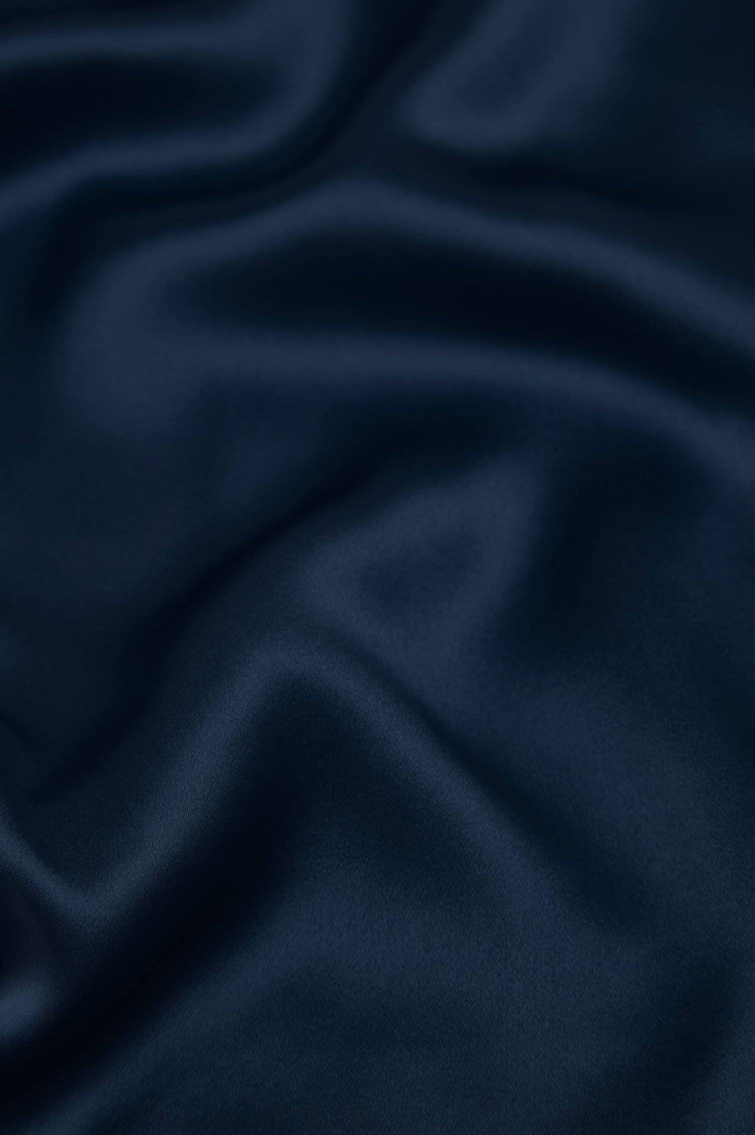 Close-up of navy silk fabric with a smooth, soft texture and gentle folds—ideal for the Coco Silk Pajamas by Olivia von Halle.