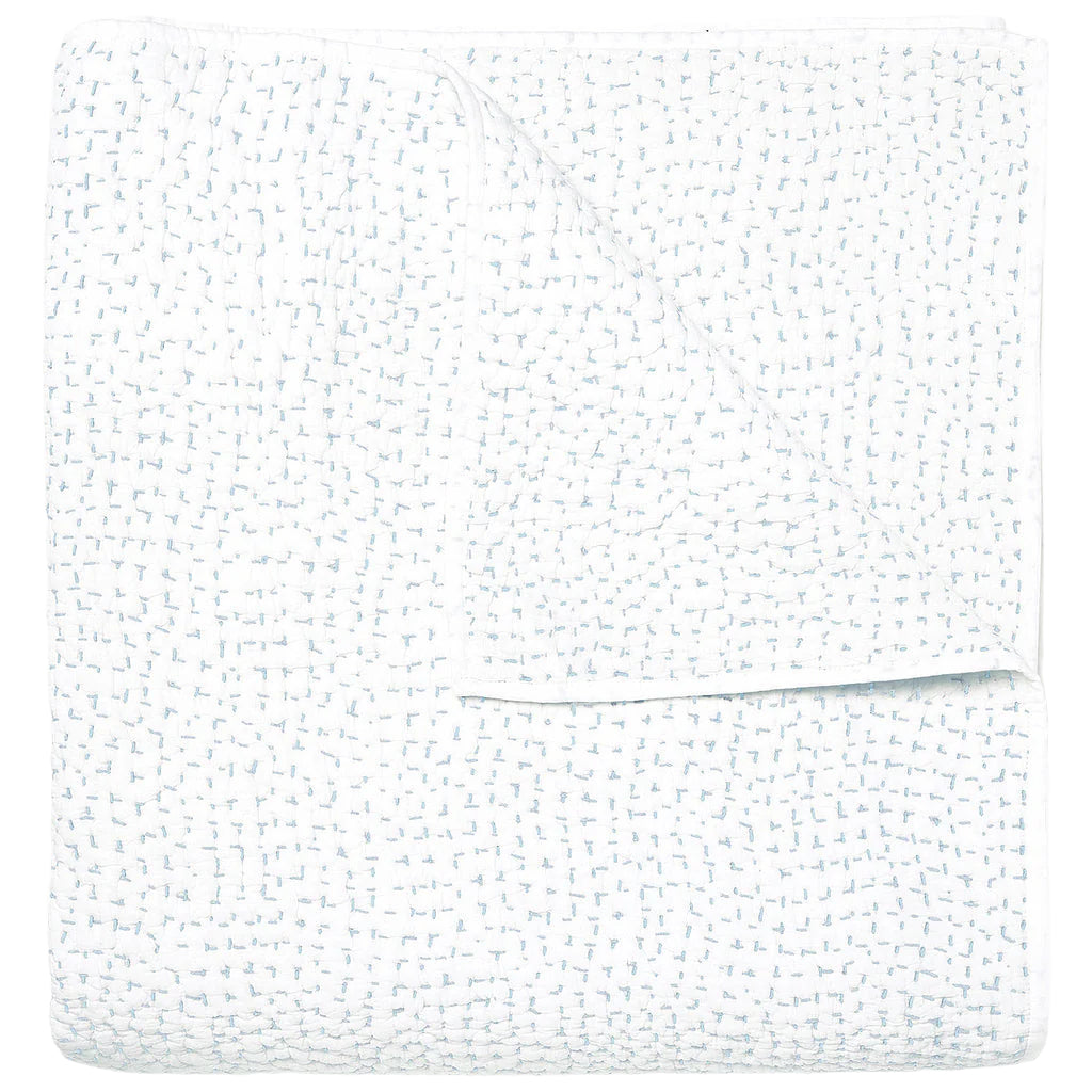 The Stitched Mist Coverlet by John Robshaw is a folded white organic cotton voile blanket with a subtle grid texture and faint blue stitching, displayed on a plain white background.