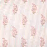 The Nirvi Lotus Bedding Collection by John Robshaw features pink and green floral sprigs in a charming block print style, repeating neatly over a beige and white subtly striped background.