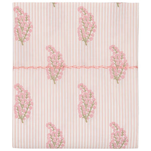 The Nirvi Lotus Bedding Collection by John Robshaw features folded fabric with subtle light pink and white stripes, floral block prints in pink and green clusters, and a pink stitched line across the middle.