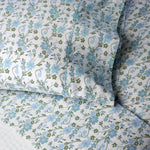 Close-up of a pillow and bed sheet from the John Robshaw Mihana Mist Bedding Collection, featuring a blue and green floral pattern on white 400 thread count organic cotton for botanical harmony in your bedroom.