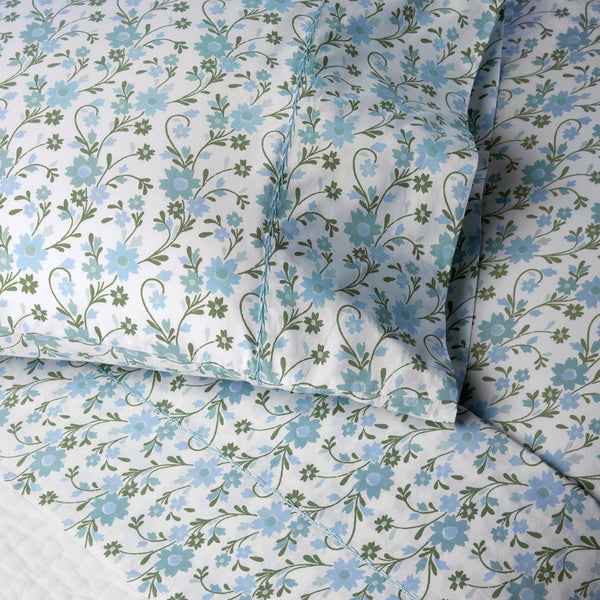 Experience botanical harmony with the John Robshaw Mihana Mist Bedding Collection. This set features blue flowers and green vines on a white background, crafted from luxurious 400 thread count organic cotton, promising comfort and elegance for restful nights.