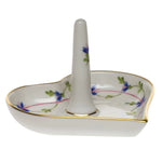 The Herend Ring Holder is a heart-shaped, hand-painted porcelain piece featuring a central upright post, delicate blue flower accents, and elegant gold trim.
