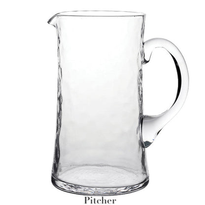 A Juliska Puro Glass Serveware pitcher with a handle and subtle textural lines stands upright on a white background, with "Pitcher" written below the image.