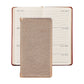 A Graphic Image 2027 Pocket Datebook with a metallic cover is placed on top of an open weekly planner showing dates from July 12 to July 18.