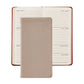 An open planner displays a week in July, topped with a closed Graphic Image 2027 Pocket Datebook in beige leather.