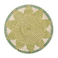 The Kim Seybert Majorelle Placemat features a round, woven design in green, beige, and white geometric patterns, crafted from natural seagrass and viewed from above.