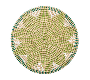 The Kim Seybert Majorelle Placemat is a round woven piece with a green, white, and teal spiral pattern. Made from natural seagrass, it offers both elegance and durability.