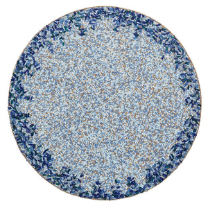 The Kim Seybert Lagoon Placemat showcases a circular mosaic design with a densely patterned blue and brown center accented by cobalt blue beads, bordered by deep ocean-inspired blue and green tones.
