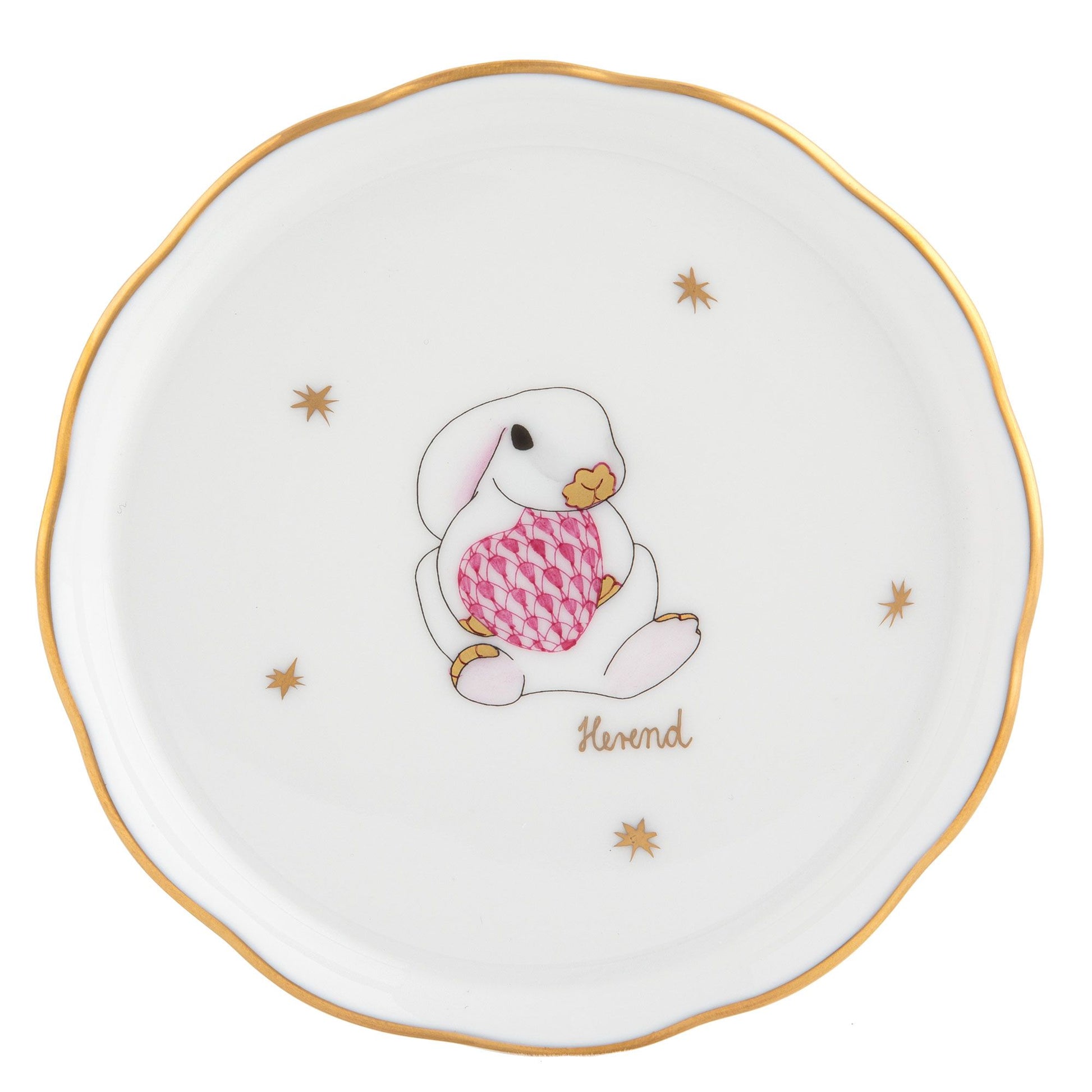 Herend Bunny Coaster: White porcelain with a gold rim, featuring a bunny holding a pink patterned egg, gold stars, and the word "Herend." Handcrafted in Hungary.