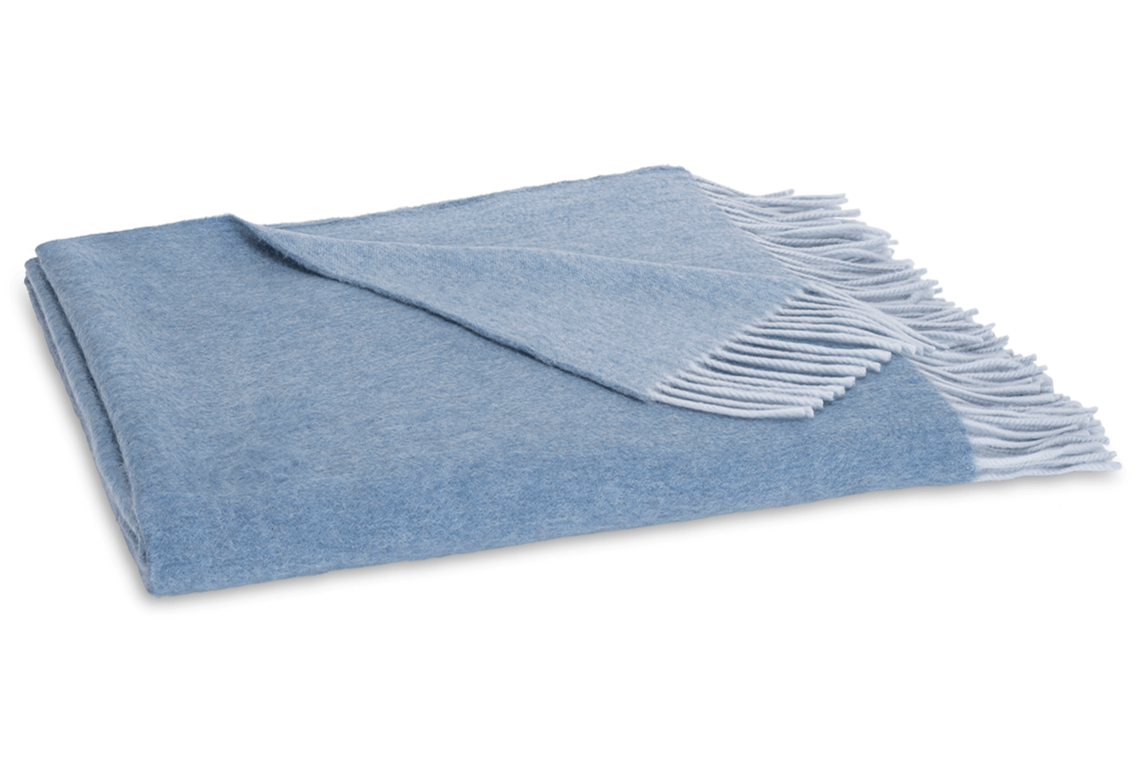 The Paley Cashmere Throw by Matouk, in light blue Mongolian cashmere with a fringed edge, is shown folded on a white background.
