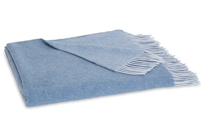 The Paley Cashmere Throw by Matouk, in light blue Mongolian cashmere with a fringed edge, is shown folded on a white background.
