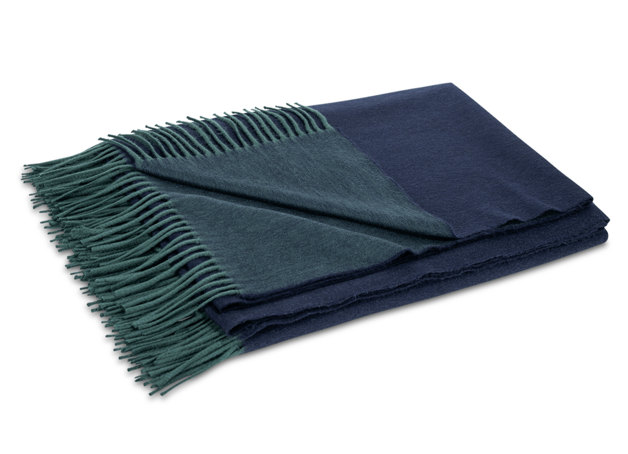 The Matouk Paley Cashmere Throw, a folded reversible design in navy blue and dark green with green fringed edges, is shown on a plain light background.