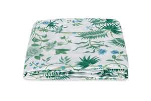 The Palmyra Bedding Collection in Emerald by Matouk features a neatly folded white bedsheet adorned with green palm fronds and a floral print on a plain background.