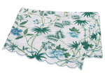 The Matouk Palmyra Bedding Collection, Emerald, features a folded tablecloth with green and blue palm fronds and leafy patterns on a white background, finished with a scalloped edge.