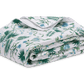 The Matouk Palmyra Bedding Collection, Emerald, features a folded quilt with a white background and an emerald green and blue botanical print on soft Egyptian cotton percale—ideal for lovers of luxurious tropical print bedding.