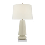 The Parisienne Lamp Collection by Visual Comfort features a modern table lamp with a white cylindrical shade and a glossy, geometric cream ceramic body on a square base, creating an inviting ambient glow.