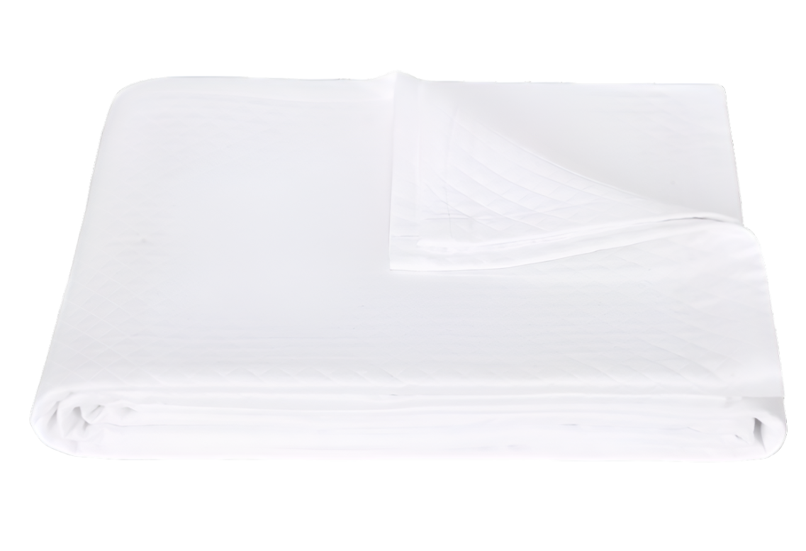 The Matouk White Petra Bedding Collection mattress protector, crafted from white cotton with a quilted matelassé pattern, is neatly folded and displayed on a plain white background.