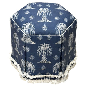 Experience comfort and style with the Evans Skirted Ottoman by Highland House—a hexagonal blue ottoman featuring custom fabric, white palm tree patterns, white piping, and a fringed base trim.