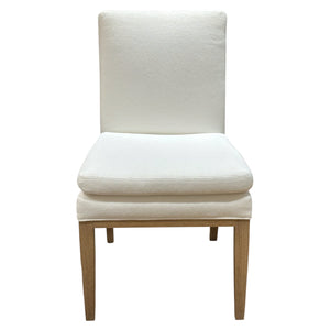 The Decker Side Chair by Ferrell Mittman features a simple white cushion, wooden frame, and straight legs, shown here from the front against a plain background.