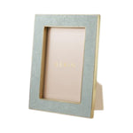 From the Classic Shagreen Frame Collection by Aerin, this rectangular frame features a light blue embossed shagreen border and polished brass edges, and stands upright with "AERIN" shown on the insert.