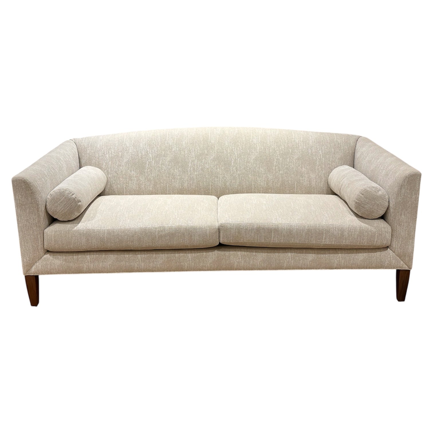The Ferrell Mittman Norman Sofa in Tinto features elegant beige upholstery, two seat cushions, cylindrical bolsters, angled arms, and wooden legs.