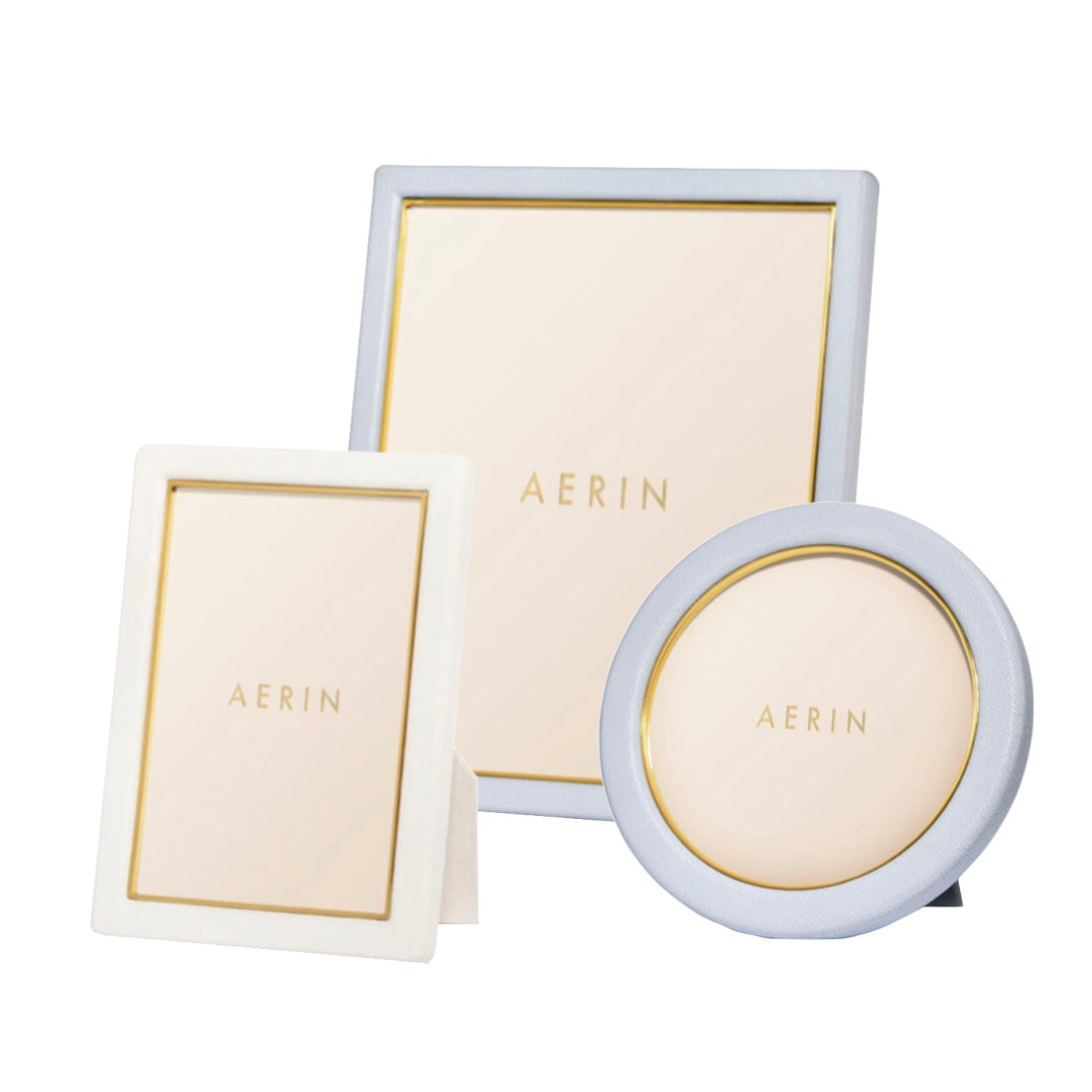 The Piero Leather Frame Collection by Aerin includes rectangular, square, and round frames with gold detailing and Italian leather, creating an elegant display on a white background.