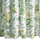 The Pomegranate Shower Curtain Collection by Matouk showcases a white backdrop adorned with green and yellow botanical prints of assorted leaves, flowers, and plants in a detailed, symmetrical design—crafted from luxurious Luca percale and inspired by Schumacher’s iconic botanical motifs.