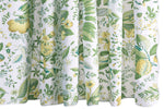The Pomegranate Shower Curtain Collection by Matouk showcases a white backdrop adorned with green and yellow botanical prints of assorted leaves, flowers, and plants in a detailed, symmetrical design—crafted from luxurious Luca percale and inspired by Schumacher’s iconic botanical motifs.