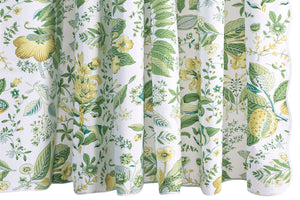 The Pomegranate Shower Curtain Collection by Matouk showcases a white backdrop adorned with green and yellow botanical prints of assorted leaves, flowers, and plants in a detailed, symmetrical design—crafted from luxurious Luca percale and inspired by Schumacher’s iconic botanical motifs.