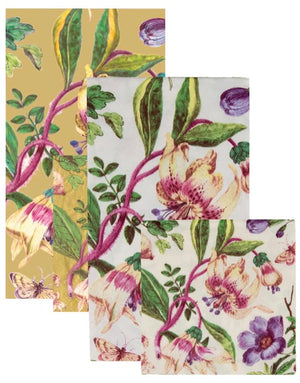 The Caspari Porcelain Blooms Collection features three overlapping triple-ply napkins in yellow, white, and cream, with purple, green, and pink floral patterns. These eco-friendly napkins add style to any table setting.