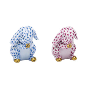 The Herend Praying Bunny set features two ceramic figurines with gold accents and hand-painted designs: one in blue and white, the other in pink and white. Placed side by side, they invite artistic appreciation.
