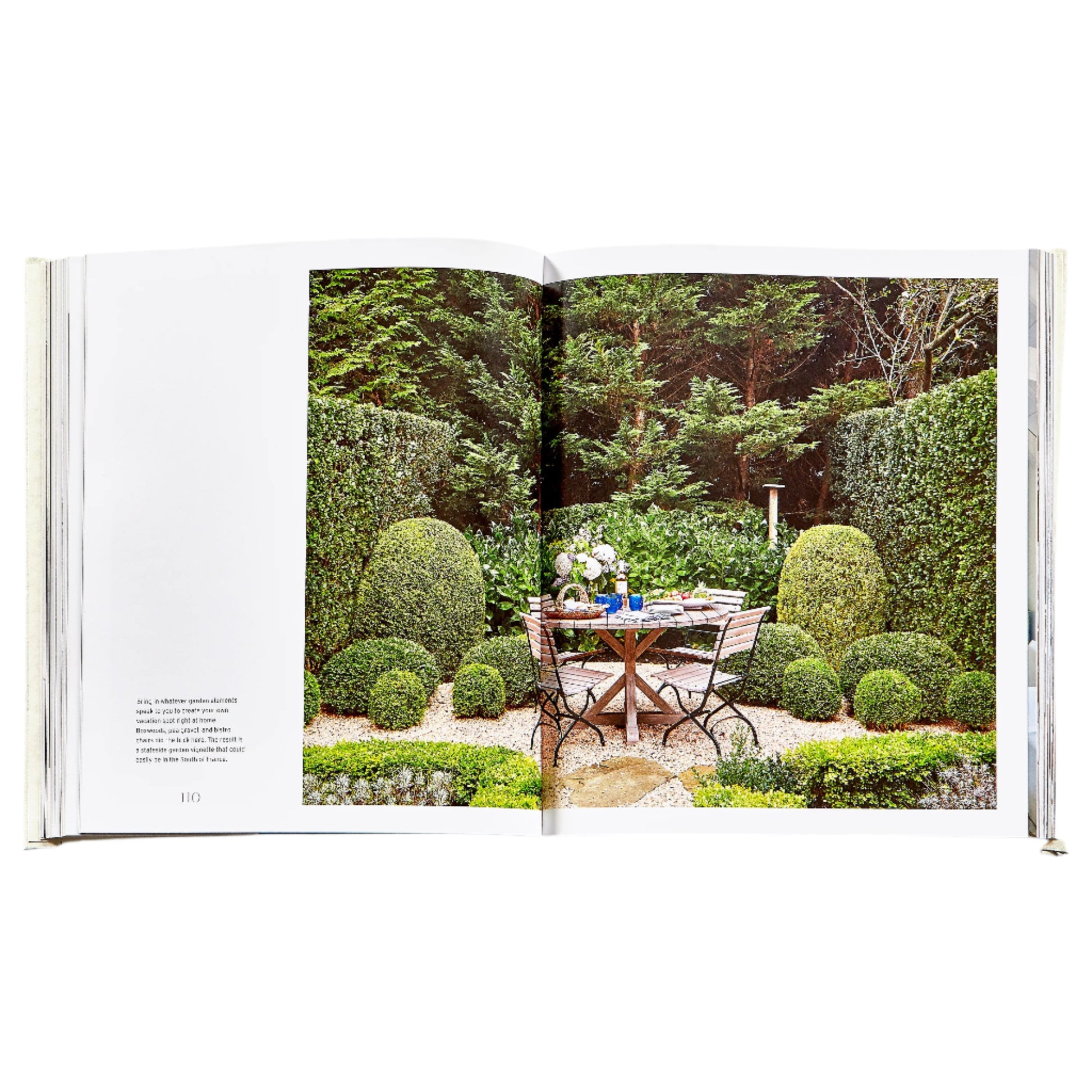 An open spread of The Principles of Pretty Rooms by Graphic Image shows a formal garden with a round table and two chairs—an inspiring scene for interior designers seeking timeless interiors and beautiful color palettes.