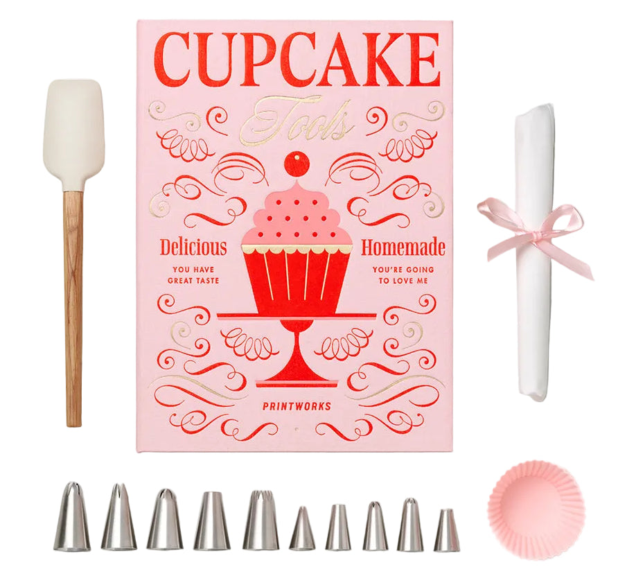 The Essentials Cupcake Tools by PrintWorks includes a spatula, recipe booklet, piping tips, a rolled cloth with a pink ribbon, and a pink cupcake liner—all stylishly displayed on a white background.