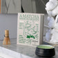 A box labeled "A Matcha Made in Heaven" sits on a marble counter beside PrintWorks' The Essentials Matcha Tools x Café Kitsuné kit, featuring a matcha whisk, green bowl with bamboo spoon, and a glossy white decorative sculpture.