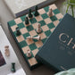 The PrintWorks Chess Collection features a green and beige chessboard with scattered pieces, set among books and décor—an elegant choice for lovers of classic board games.