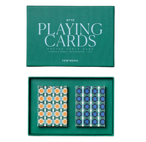 The PrintWorks Playing Cards set includes two geometric-design decks—one orange and light blue, the other blue and dark blue—placed side by side in a green box labeled "Playing Cards.