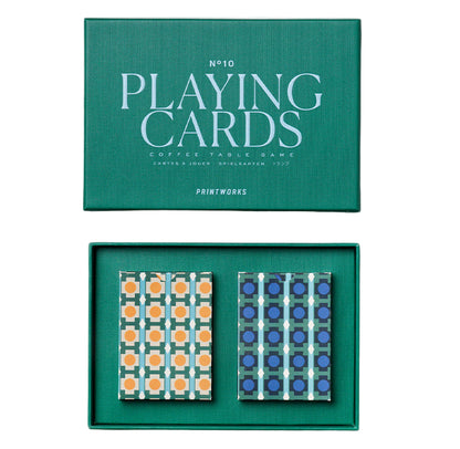 The PrintWorks Playing Cards set includes two geometric-design decks—one orange and light blue, the other blue and dark blue—placed side by side in a green box labeled "Playing Cards.