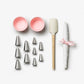 The Essentials Cupcake Tools by PrintWorks includes two pink cupcake liners, nine metal piping tips, a silicone spatula with wooden handle, and rolled parchment tied with a pink ribbon—all presented on a white background.