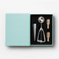 The Essentials Ice Cream Tools by PrintWorks includes an ice cream scoop, metal cone, and two wooden-handled stainless steel tools in a black foam insert—everything you need for your next ice cream party.