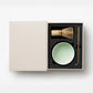 Discover The Essentials Matcha Tools x Cafe Kitsuné by PrintWorks: a boxed set with bamboo whisk, light green ceramic bowl, and metal scoop—all nestled in foam. Ideal for Café Kitsuné fans and matcha lovers alike.