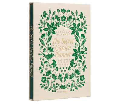 The PrintWorks Secret Garden Journal is a hardcover gardening planner with green floral designs on a beige cover, shown upright and slightly angled left. Ideal as a plant tracker or garden journal.