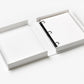 A Dream Big Little One Photo Album by PrintWorks, styled like a baby milestone book, lies open with its white cover fully extended on a flat surface, displaying blank pages held by three rings.