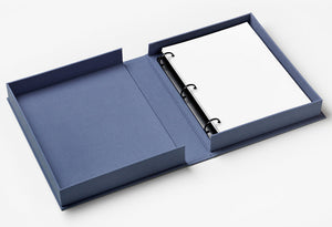 The PrintWorks Blue Picture Perfect Photo Album lies open, displaying a ring-bound stack of high-quality photo paper on the right and an empty compartment on the left.