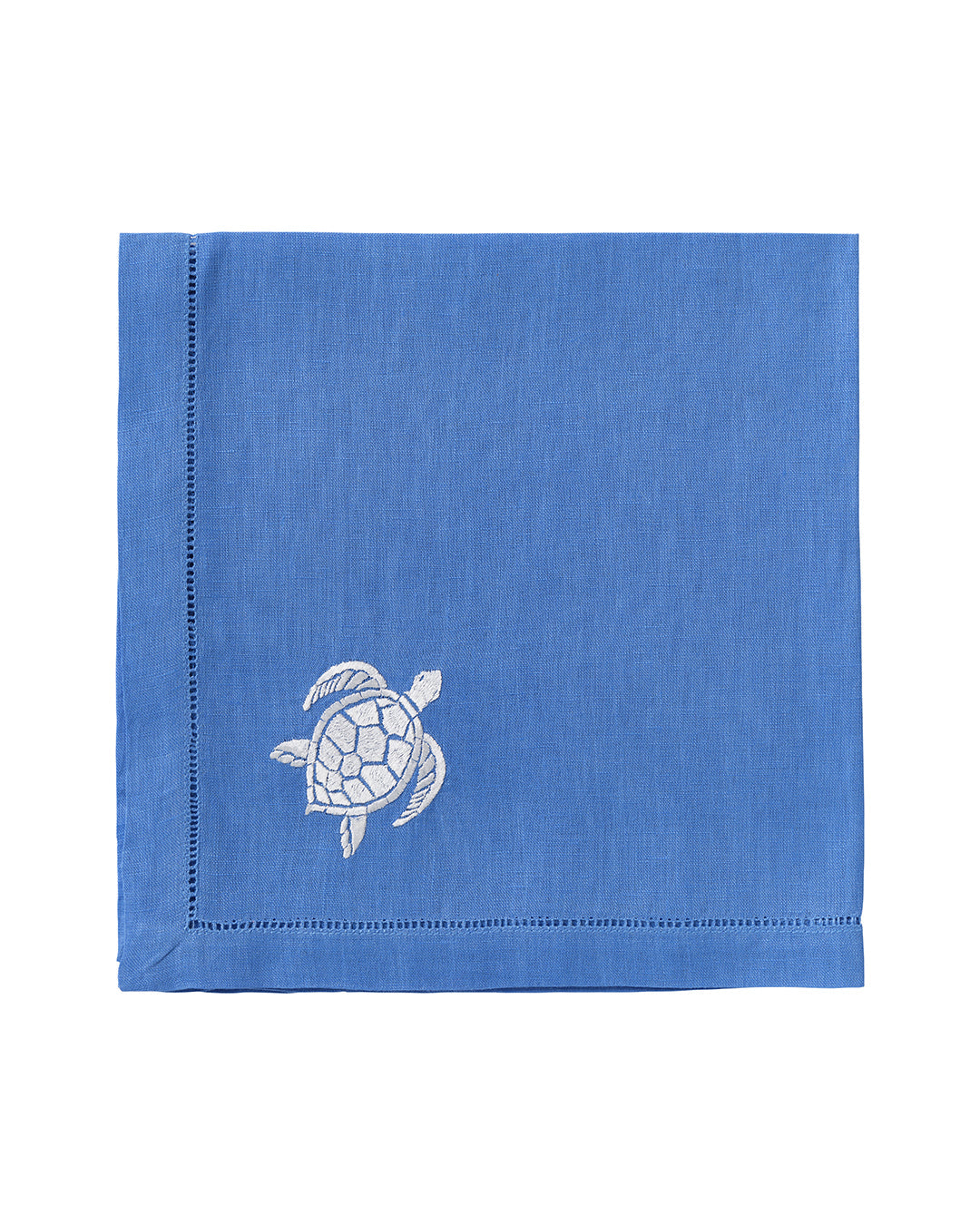 The Pink House Mustique Dinner Napkin Set features folded blue linen napkins with a white embroidered turtle in one corner, adding elegance to your luxury table linen collection.