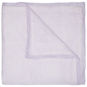 The John Robshaw Nandi Lavender Coverlet features a folded, light lavender hue with subtle vertical stripes, and one corner flipped to reveal its block-printed cotton voile underside.